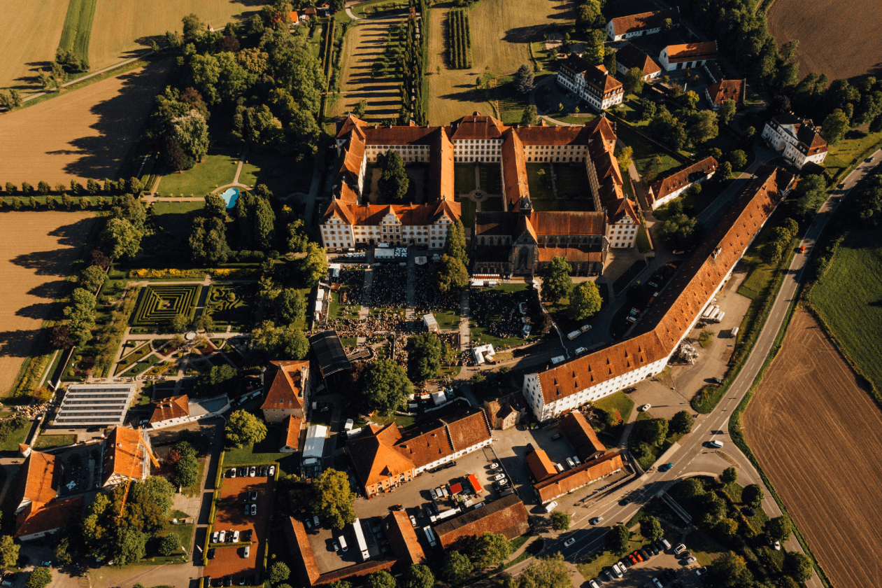 Konzertbesucher im Schlossgarten Salem bei Abendstimmung und beleuchteter Bühne.