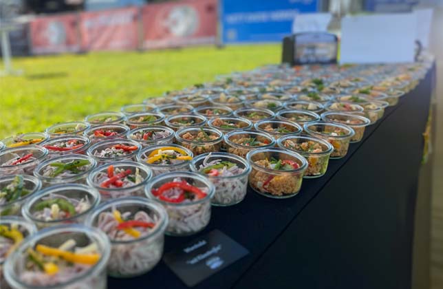 Viele kleine Gläser mit bunten Speisen auf schwarzem Tisch bei Outdoor-Event