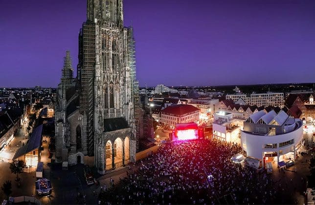 Konzertbühne auf dem Münsterplatz vor dem hell erleuchteten Ulmer Münster bei Nacht.